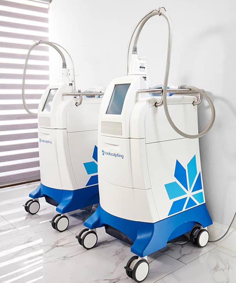 Two CoolSculpting (Dual Sculpting) machines in a room, with cooling applicators attached.