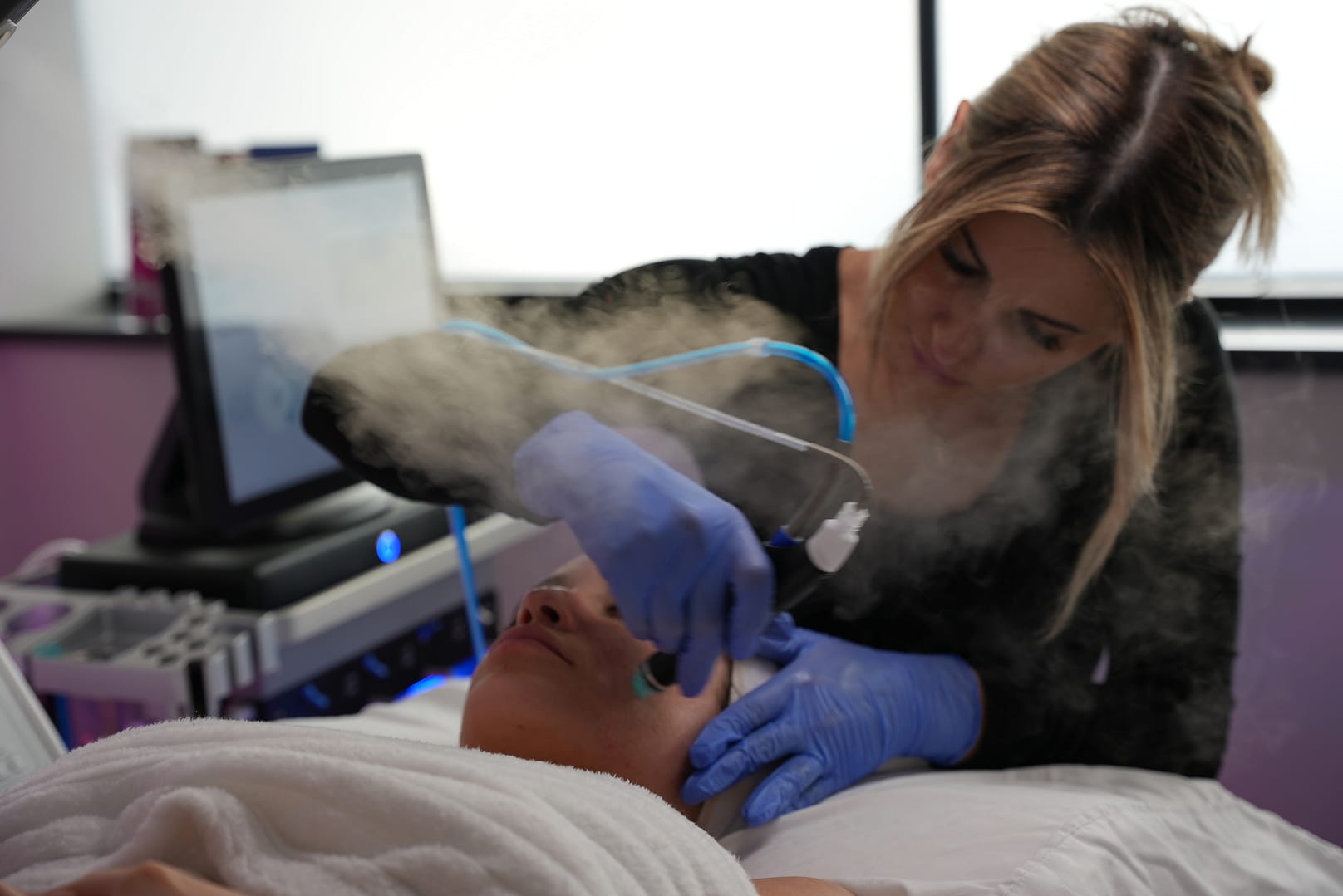 An image of Hydrafacial treatment executed by a female esthetician at Bloom Health.
