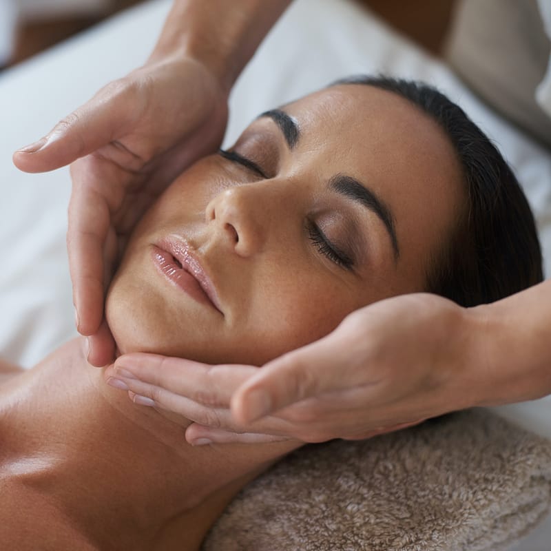 Closeup image of an attractive woman enjoying a face massage.